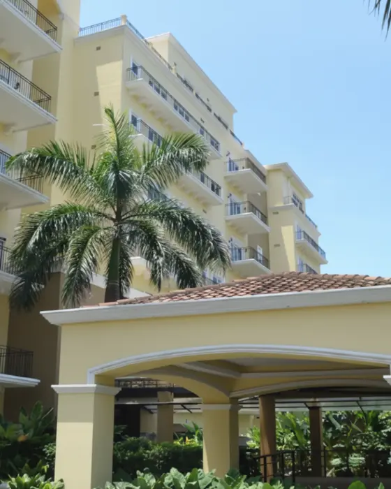 Edificio residencial con balcones, jardines tropicales y palmeras