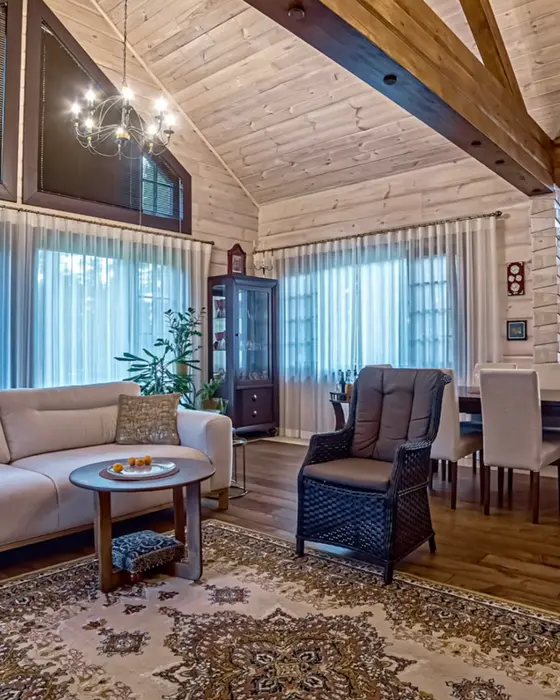 Sala y comedor de estilo rústico con techo alto y vigas de madera